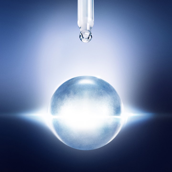 Lancôme Génifique Ultimate Serum 50 ml fugtgivende ansigtsserum med en dråbe fra en pipette over en lysende blå sfære
