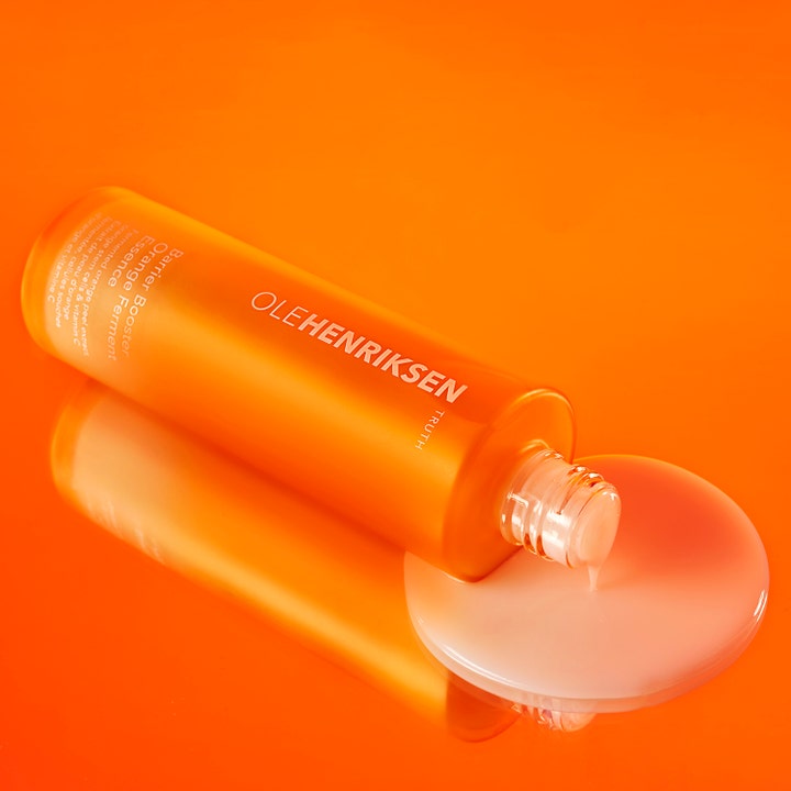 Ole Henriksen Truth Barrier Booster Ferment Essence 118 ml ansigtsvatten med flydende tekstur på orange baggrund