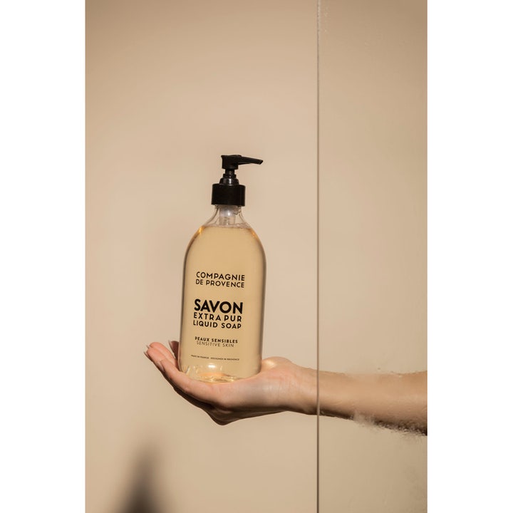 Compagnie de Provence Liquid Marseille Soap Sensitive Skin 495 ml flydende sæbe i gennemsigtig flaske holdt i en hånd
