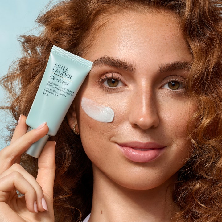 Estée Lauder DayWear Sheer Tint Release Moisturizer 15 ml fugtgivende dagcreme med SPF 15 i lyseblå tube på en kind.