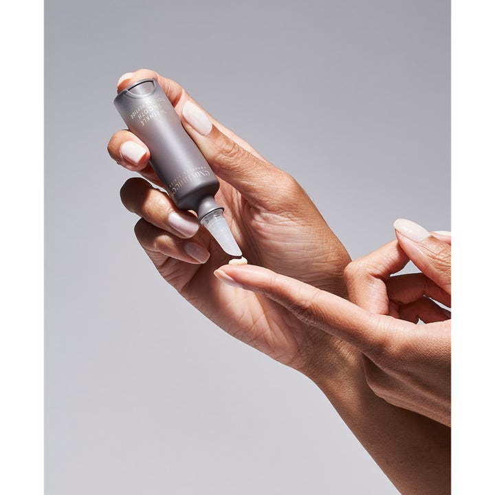 Exuviance Wrinkle Smooth Topical Peptide 5 g serum mod rynker med cremet tekstur på en fingerspids.