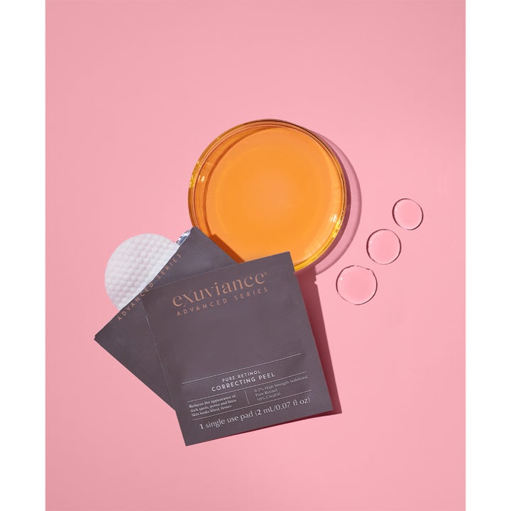 Exuviance Pure Retinol Correcting Peel 6 stk peeling sachet og pad ved orange væske og dråber på lyserød baggrund