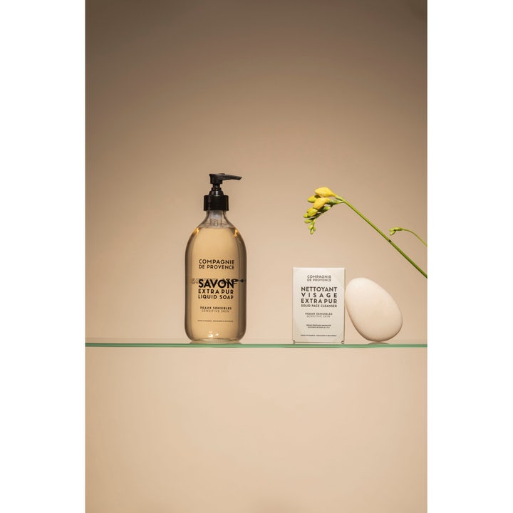 Compagnie de Provence Liquid Marseille Soap 495 ml beroligende håndsæbe ved siden af en æske og en gul blomst.