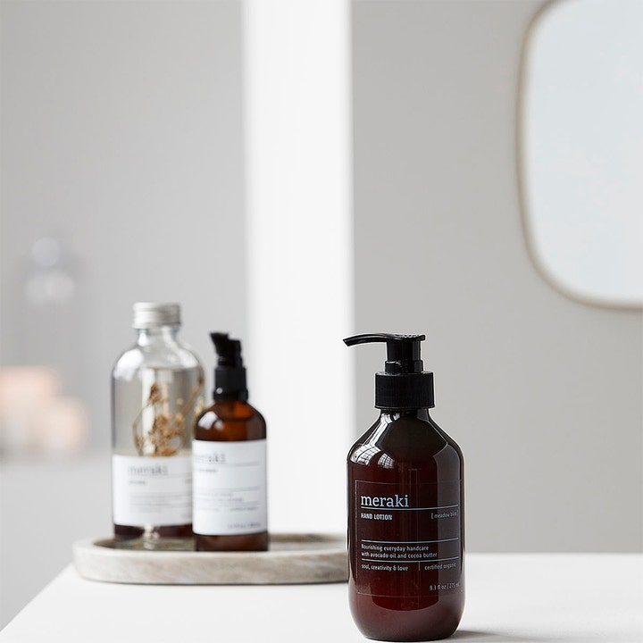 Meraki Meadow Bliss Hand Lotion 275 ml plejende håndcreme i mørk flaske med pumpe i et lyst badeværelse.