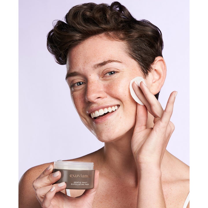 Exuviance Gentle Daily Exfoliating 60 pads peeling giver glød vist på en model der bruger en rondel på kinden