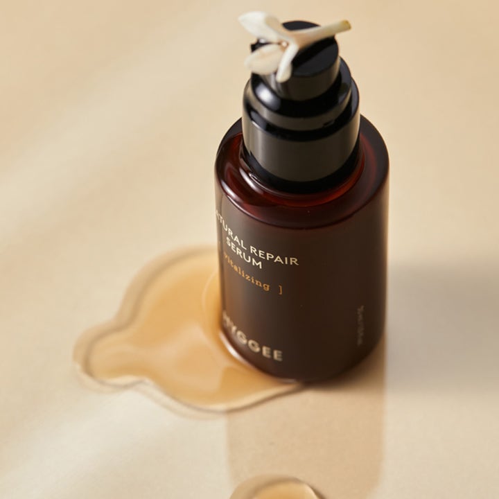 Hyggee Natural Repair Serum 30 ml vitaliserende serum i mørk glasflaske stående i en gylden dråbe med en hvid blomst