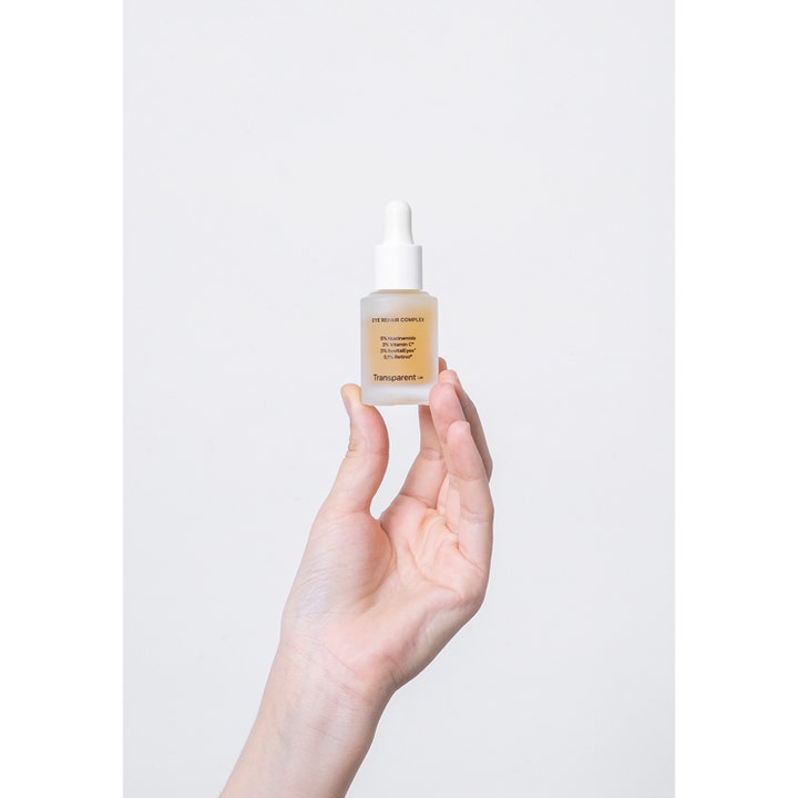 Niche Beauty Lab Transparent Lab Eye-Repair Complex 15 ml øjencreme i frostet glasflaske holdt i en hånd.