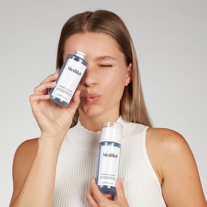 Medik8 Press & Clear 150 ml eksfolierende BHA toner i blå flasker holdt af en kvinde for klar hud