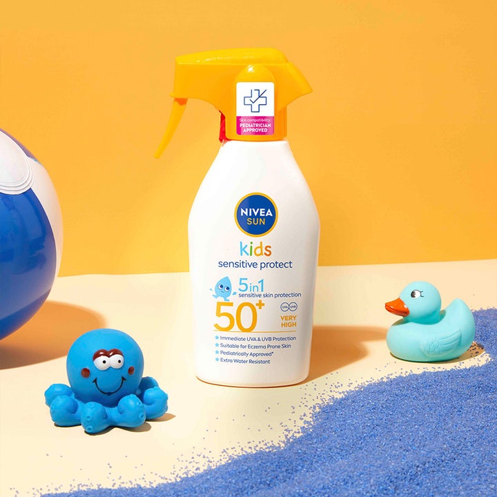 NIVEA Kids Sensitive Protect & Play 270 ml SPF 50+ solcreme til børn i hvid sprayflaske ved siden af blåt badelegetøj.