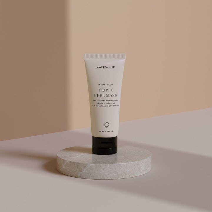 Löwengrip Instant Glow Triple Peel Mask 60 ml vegansk ansigtsmaske i beige tube på en rund marmorbase.