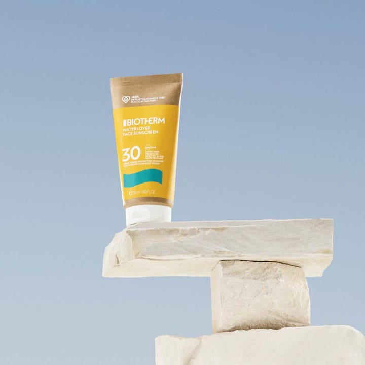 Biotherm Waterlover Face Cream SPF30 50 ml ansigtssolcreme i gul tube stående på lyse sten mod en klar blå himmel.