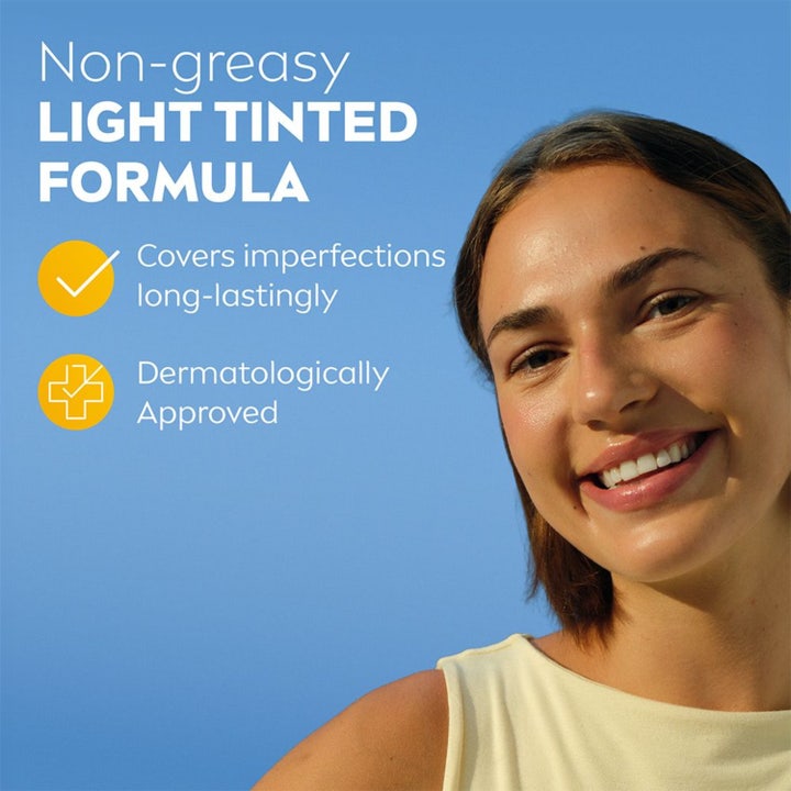 NIVEA UV Face Ultra Fluid Light Tinted SPF50+ 40 ml solcreme dækker urenheder vist på smilende kvinde mod blå himmel