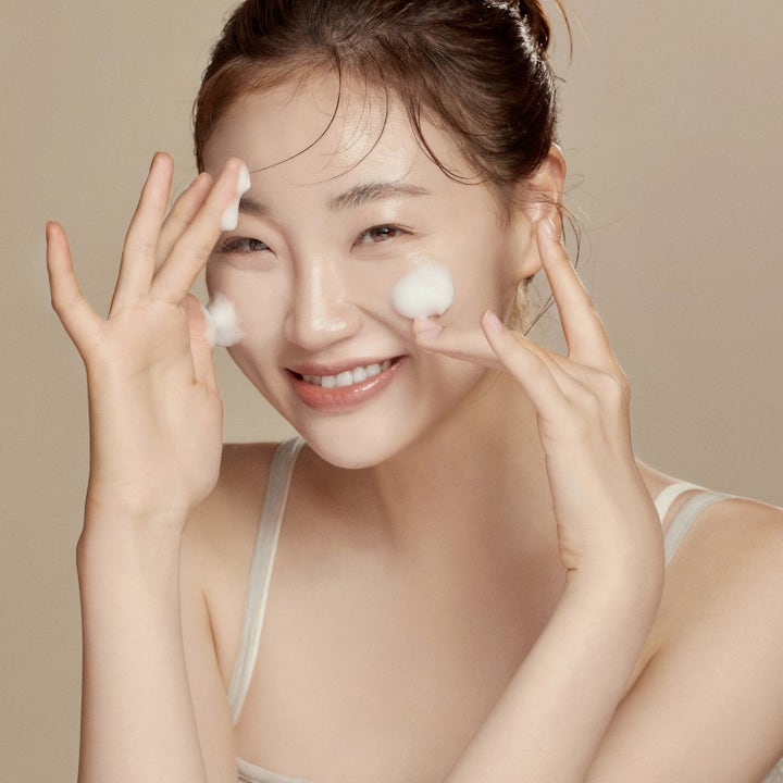 Hyggee All-In-One Care Cleansing Foam 150 ml fugtgivende rengøringsskum på en smilende kvinde for skånsom rens