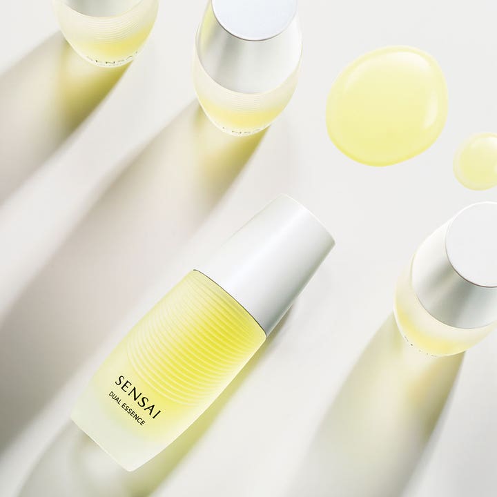 Sensai Dual Essence 30 ml fugtgivende essence med gule oliedråber og teksturerede flasker med sølvlåg