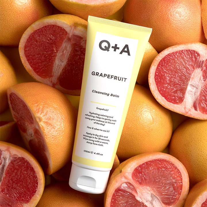 Q+A Grapefruit Cleansing Balm 125 ml fugtgivende ansigtsrens i gul tube omgivet af friske, opskårne grapefrugter