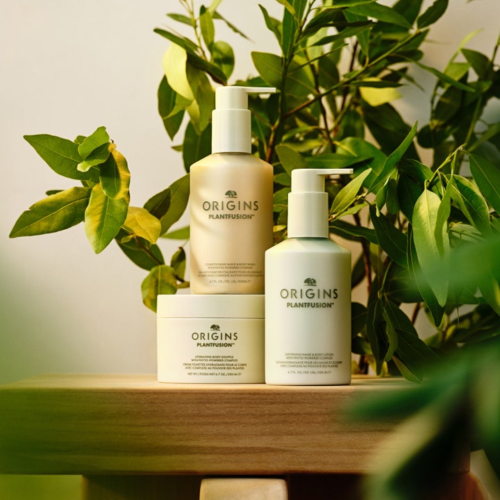 Origins Plantfusion Hydrating Body Souffle 200 ml fugtgivende bodylotion i hvid krukke placeret på træ blandt grønne blade