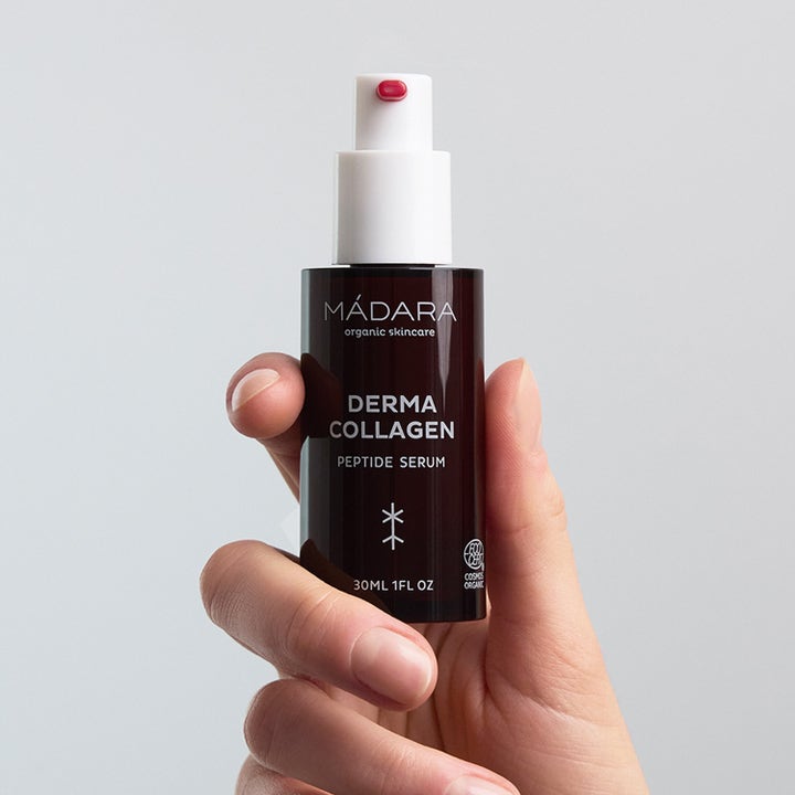 MÁDARA Derma Collagen Peptide Serum 30 ml opstrammende serum i mørk flaske med hvid pumpe i en hånd
