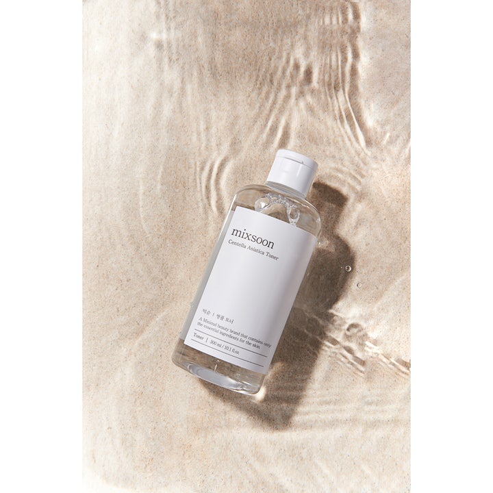 Mixsoon Centella Asiatica Toner 300 ml beroligende toner i klar flaske placeret på sand i vandkanten