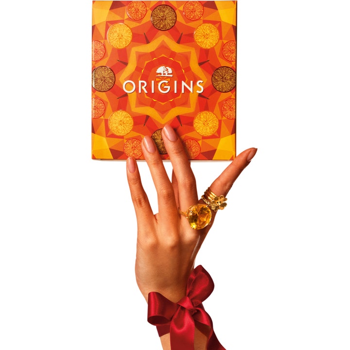 Origins Ginzing Glowing Essentials Set hudplejesæt for glød i mønstret orange æske holdt af hånd med rød sløjfe