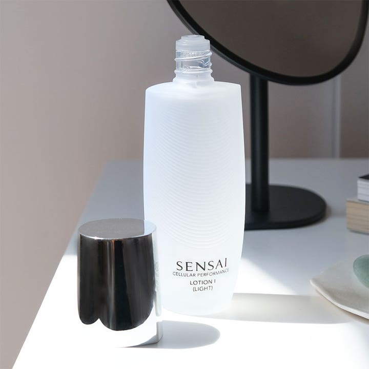 Sensai Cellular Performance Lotion I Light 125 ml toner i hvid frostet flaske med sølvlåg ved et spejl