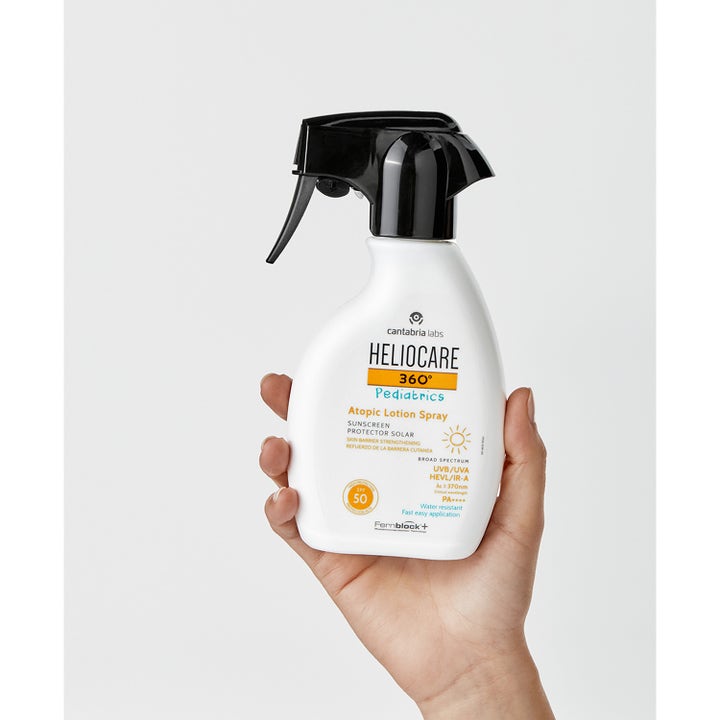Heliocare Pediatrics Atopic Lotion Spray 250 ml solcreme giver SPF 50 beskyttelse i hvid sprayflaske holdt af en hånd