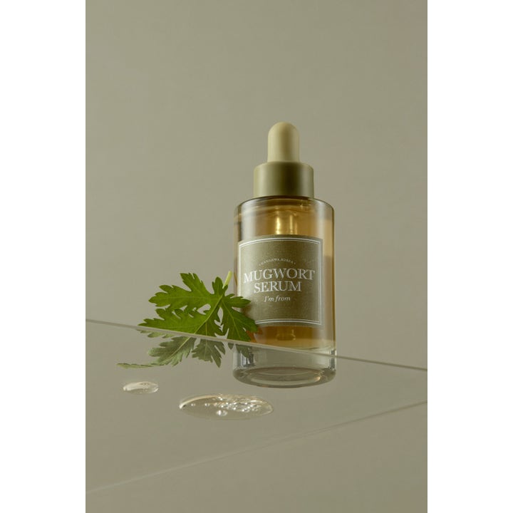 I'm from Mugwort Serum 30 ml beroligende ansigtsserum i glasflaske med pipette ved siden af et frisk grønt blad