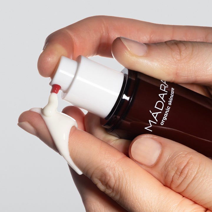 MÁDARA Derma Collagen Peptide Day Cream 50 ml opstrammende dagcreme i mørkebrun flaske med hvid creme på en finger