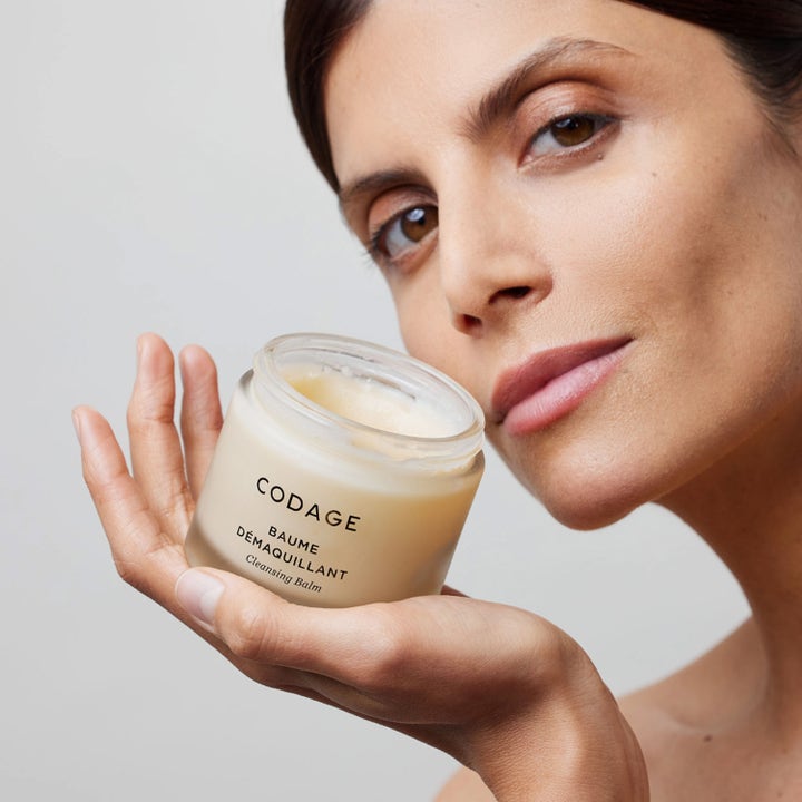 Codage Paris The Cleansing Balm 100 ml ansigtsrens i en frostet glaskrukke holdt af en kvinde.