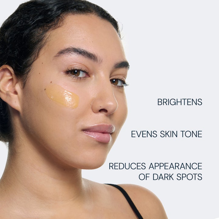 Elemis Dynamic Resurfacing Super-C Serum 30 ml lysner huden og giver glød vist som gul serumtekstur på en kind.