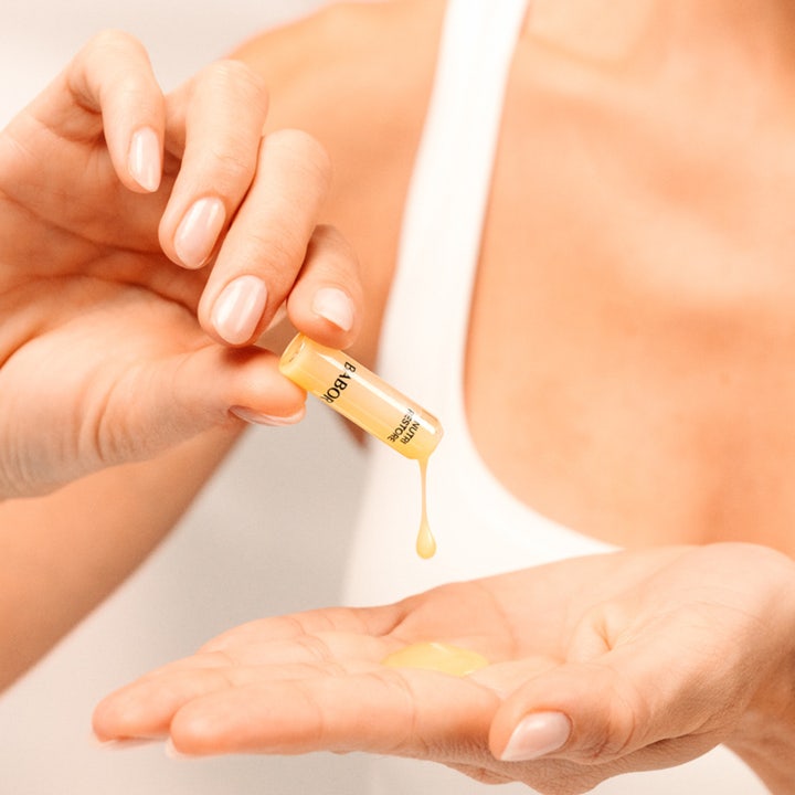 Babor Nutri Restore Ampoule 14 ml nærende ansigtsserum i en lille glasampul med gul væske i hænderne