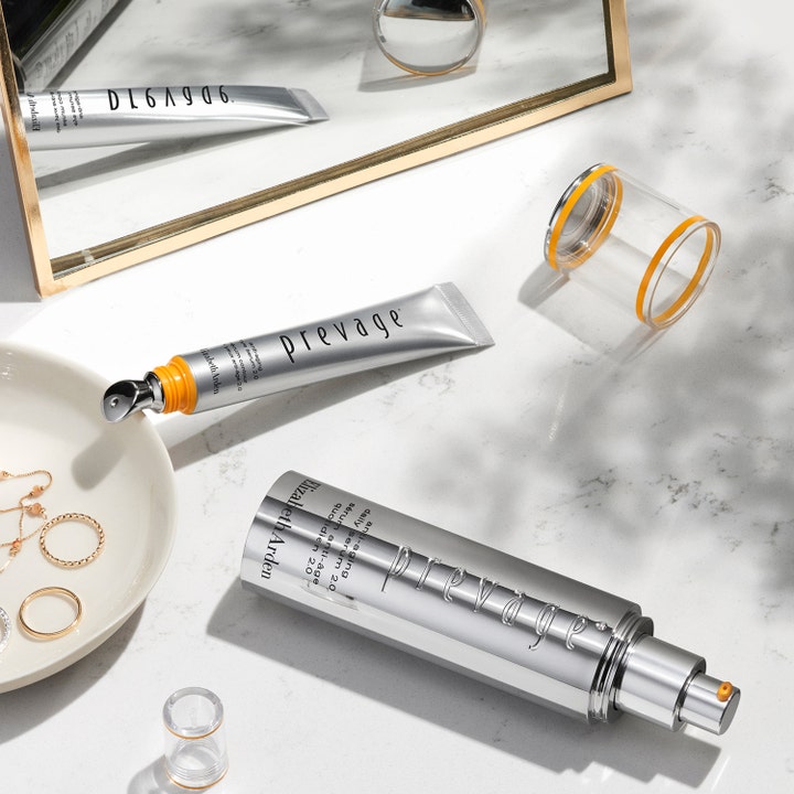 Elizabeth Arden Prevage Anti-Aging Eye Serum 2.0 20 ml øjenserum i sølvtube ved siden af smykker og et spejl.