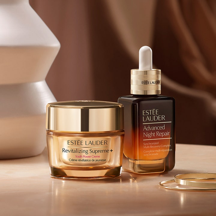 Estée Lauder Advanced Night Repair Serum 75 ml genopbyggende serum i brun glasflaske ved siden af gylden ansigtscreme.