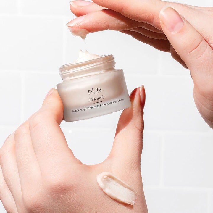 PÜR Rescue C Brightening Vitamin C & Peptide Eye Cream 15 ml i frostet krukke med cremet swatch på hånden.