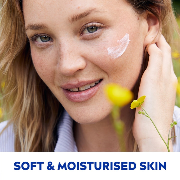 NIVEA Soft 75 ml fugtgivende creme på kinden af en smilende kvinde i en blomstermark for blød hud