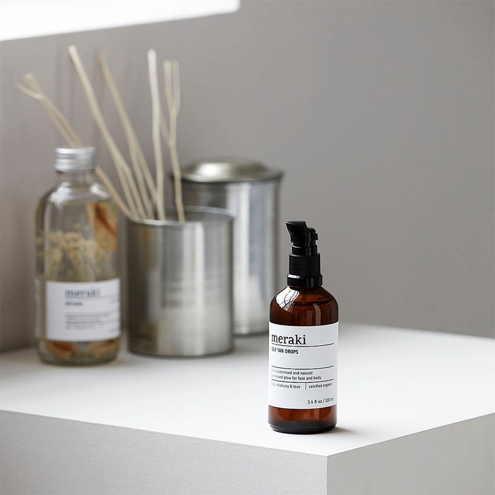 Meraki Self Tan Drops 100 ml giver glød i brun glasflaske med pumpe i et minimalistisk badeværelsesmiljø