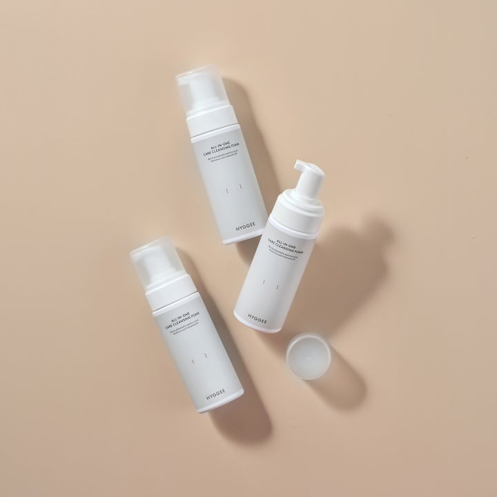 Hyggee All-In-One Care Cleansing Foam 150 ml ansigtsrens i hvide pumpeflasker på beige baggrund