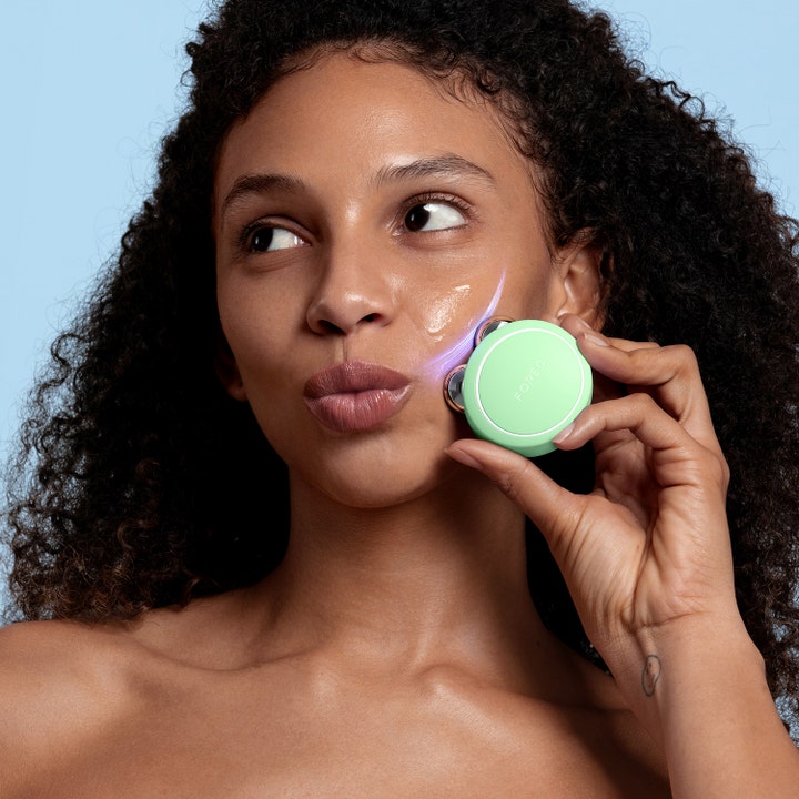 FOREO BEAR 2 go Pistachio 1 stk beauty tech til ansigtsløft vist i brug med lilla mikrostrømseffekt på kinden