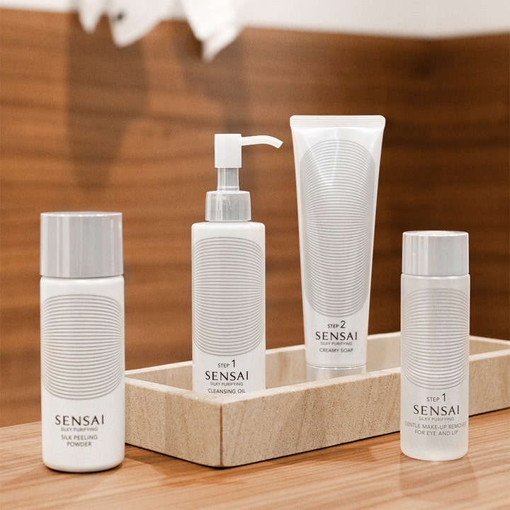 Sensai Silky Purifying Cleansing Oil 150 ml renseolie i hvid pumpeflaske i en dekorativ bakke med hudpleje.