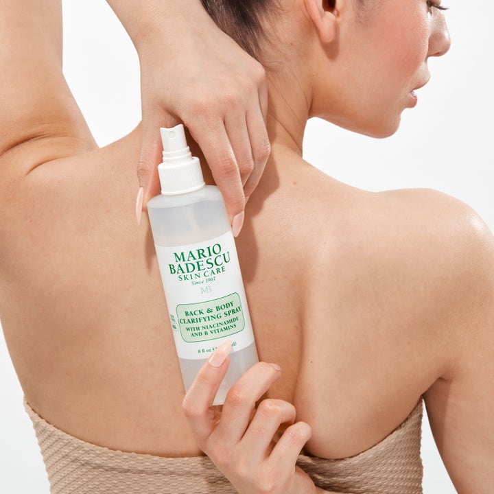 Mario Badescu Back And Body Clarifying Spray 236 ml med niacinamide og B-vitaminer holdes mod en bar ryg.