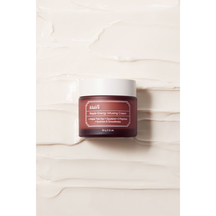 Klairs Maple Energy Infusing Cream 60 g nærende ansigtscreme i brun krukke på en baggrund af cremet tekstur.