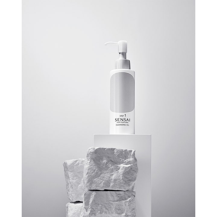 Sensai Silky Purifying Cleansing Oil 150 ml ansigtsrens i hvid pumpeflaske med mønster på hvid piedestal og sten