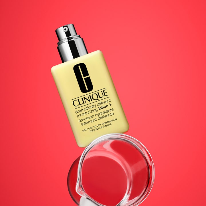 Clinique Dramatically Different Moisturizing Lotion + 125 ml fugtgivende creme i gul flaske over et glas på rød baggrund