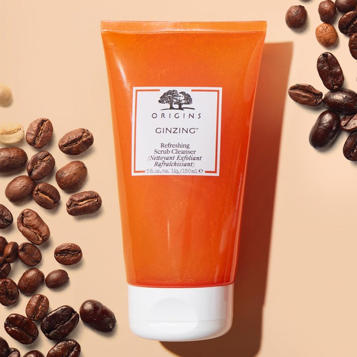 Origins GinZing Refreshing Scrub Cleanser 150 ml ansigtsskrub i orange tube omgivet af kaffebønner