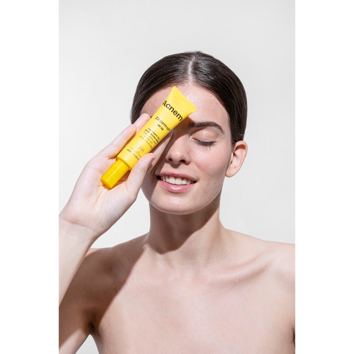 Niche Beauty Lab Acnemy Zitcontrol SPF 50 40 ml dagcreme til uren hud i gul tube holdt af en smilende kvinde