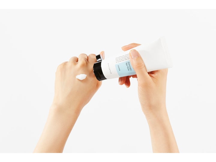 COSRX Ultimate Nourishing Rice Overnight Spa Mask 60 ml nattmaske giver fugt med hvid creme på en hånd.