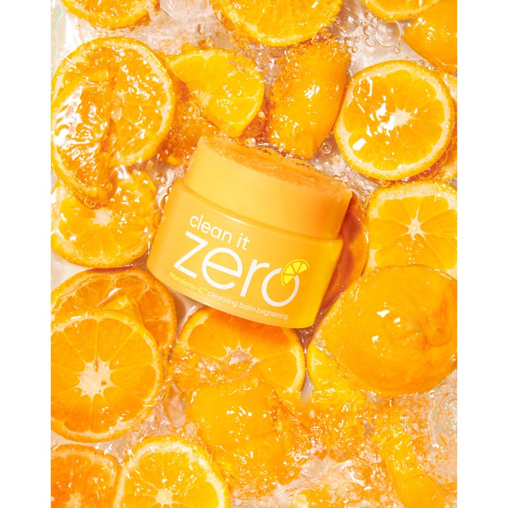 Banila Co Clean It Zero Cleansing Balm Brightening 100 ml oplysende ansigtsrens i gul krukke blandt friske appelsinskiver.