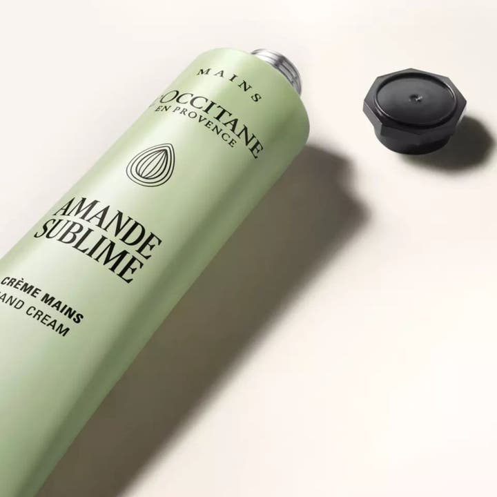 L'Occitane Almond Delicious Hands 75 ml blødgørende håndcreme i grøn tube med det sorte låg liggende ved siden af