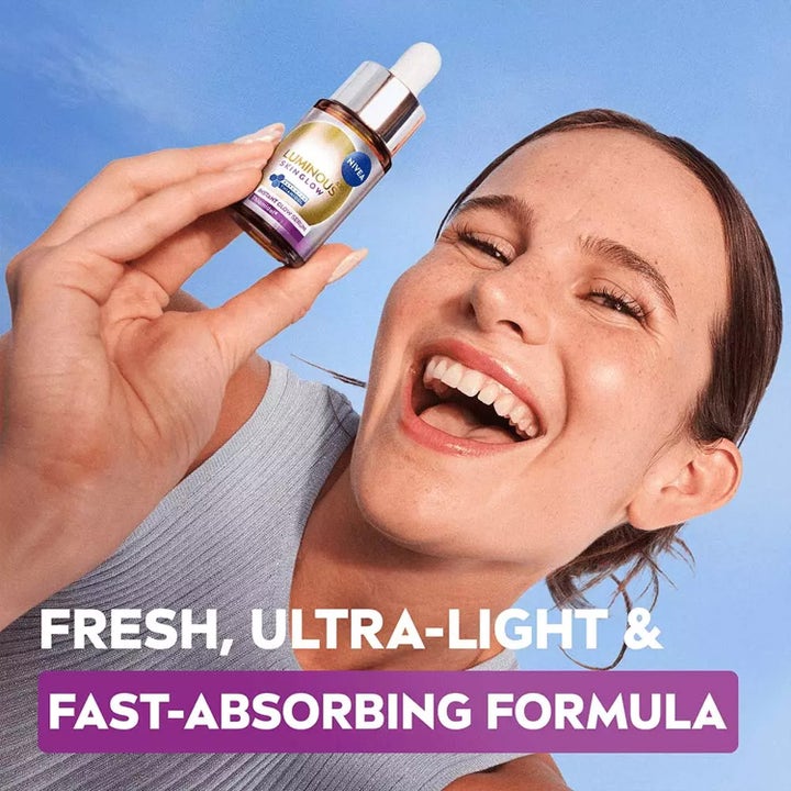 NIVEA Luminous630 Skin Glow Instant Glow 15 ml ansigtsserum i glasflaske holdt af en smilende kvinde.