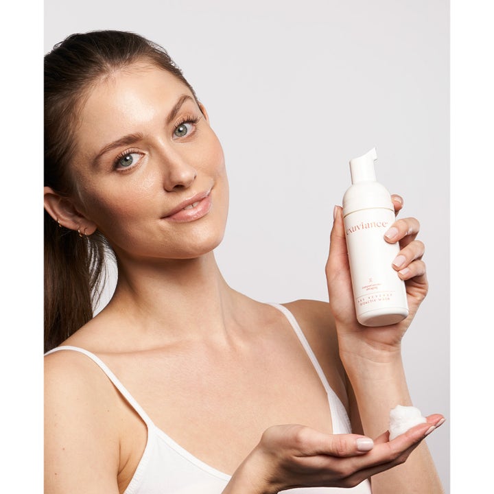 Exuviance Age Reverse BioActiv Wash 125 ml ansigtsrens mod aldringstegn vist af kvinde med flaske og skum