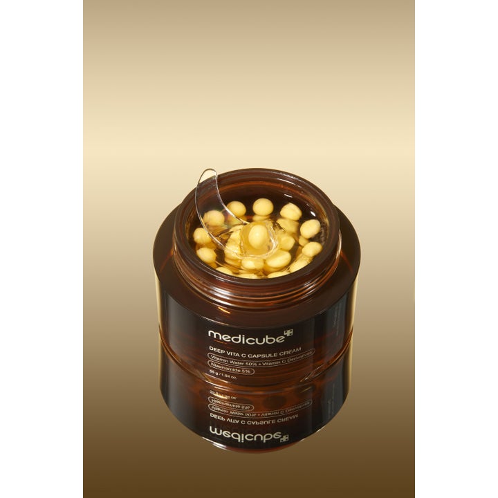 Medicube Deep Vita C Capsule Cream 55 g ansigtscreme med gule vitaminkapsler og spatel i brun krukke